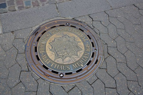 Round manhole cover with inscription fortress and memorial to engraver Matthäus Merian 1645, city