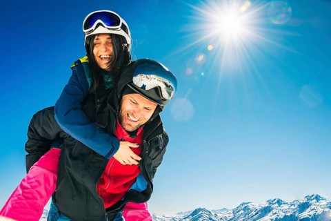 Romantic happy skiers couple in love having fun together playing in mountains piggybacking at