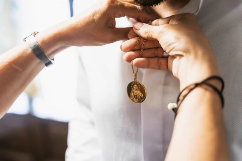 Detail of the groom's suit at the wedding, mother placing a religious brooch to give him luck at