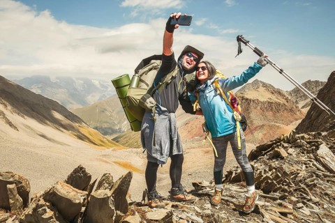 Happy couple of hikers taking selfie portrait on the top of the mountain - Smiling tourists