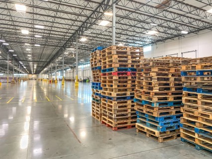 Massive Empty Industrial Warehouse Interior With Stacked Pallets