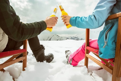 Couple relax sit on chairs in snowy ski resort with beer bottle, concept of leisure, winter