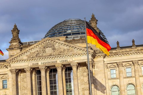 Reichstag building Berlin with German flags. Exterior view with dark clouds. Berlin, Germany