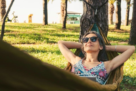 Happy Young brunette caucasian woman in hammock relax browse net work enjoy nap in park on black