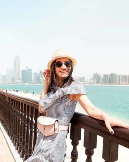 Young woman wear dress and straw hat visiting UAE capital Au Dhabi relax enjoy coastline view -