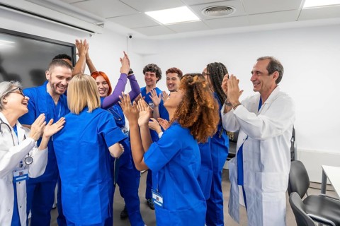 Medical team of diverse doctors and nurses clapping and offering high five gestures, showing unity,