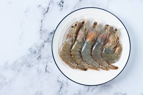 Fresh raw white-footed shrimp, tiger prawns vannamei, on a white plate