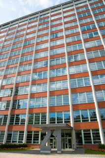 Tall office building with symmetrical window elements and a modern façade under a slightly cloudy