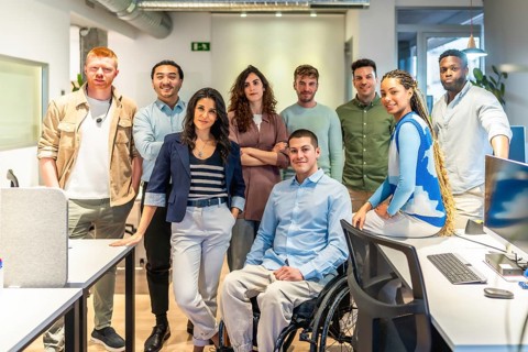 Multicultural team of professionals standing together in a modern office, showcasing diversity and