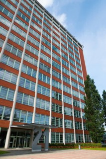 Modern office building with red brick façade and large windows under a blue sky, Batuv mrakodrap,