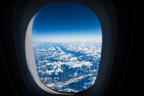 Spectacular aerial view of snow-capped mountain peaks and deep valleys seen through a commercial