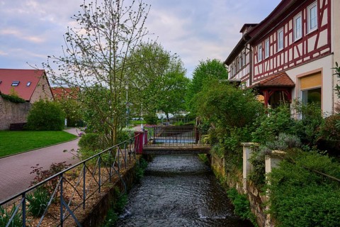 Green, idyllic landscape with half-timbered houses and a small flowing canal, spa town of Bad Orb,