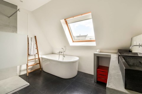 A sleek and modern bathroom featuring a freestanding tub, minimalist decor, and a unique angled