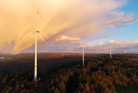 Wind turbines over a wooded hill at dusk, dramatic clouds in the sky, near Schorndorf-Winterbach,