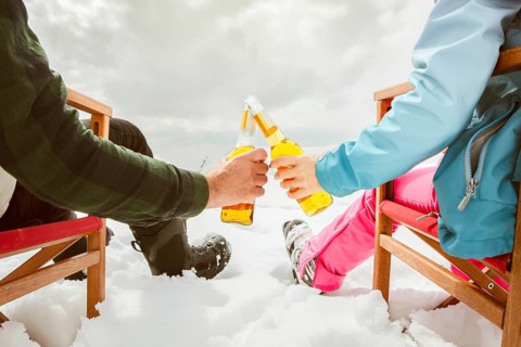 Couple relax sit on chairs in snowy ski resort with beer bottle, concept of leisure, winter