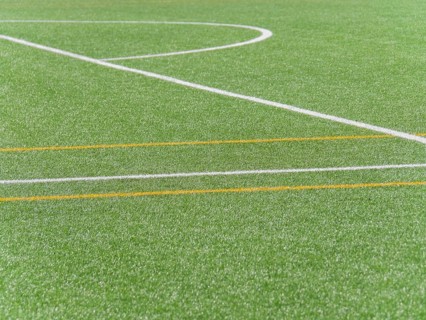 A high quality image showing a close up view of white and yellow lines on an artificial grass