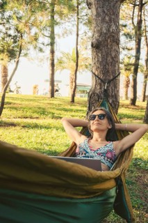 Happy Young brunette caucasian woman in hammock relax browse net work enjoy nap in park on black