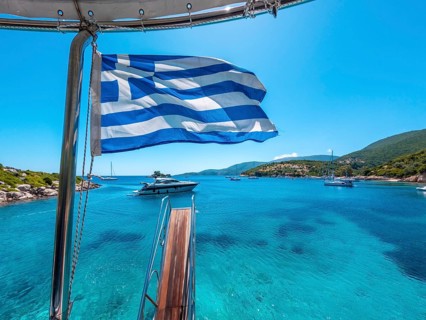 Greek flag on boat cruise around the island of Ithaki or Ithaca in the Ionian sea in the