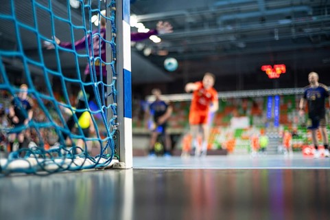 Detail of handball goal post with net and handball match in the background in Lubin, Poland