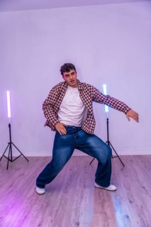 Energetic dancer showcasing urban dance moves in a studio illuminated by vibrant led lights,