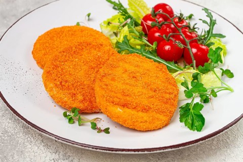 Crispy fried fish cutlets, fish burgers, on a white plate, with fresh lettuce leaves, arugula and