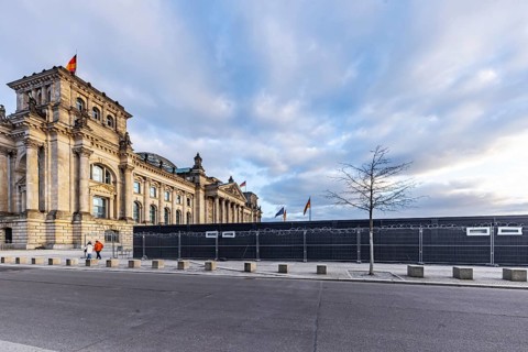 Reichstag building Berlin with German flags. Exterior view. Construction site with fence and