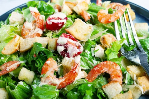 Caesar salad, with shrimp, on a marble background, top view, no people