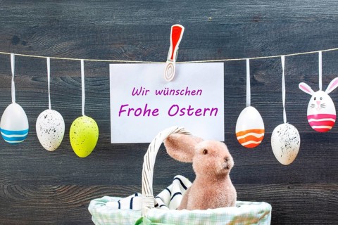 Easter decoration and a sign with (digitally added) text WIR WÜNSCHEN FROHE OSTERN in front of a