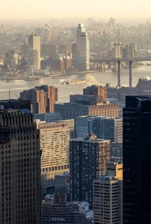 Top view of New York City at sunset, capturing the golden light casting over the buildings, river,