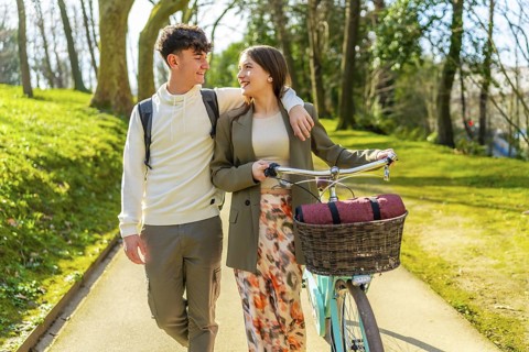 Happy couple walking together in a park, enjoying a romantic stroll with their bicycle on a sunny
