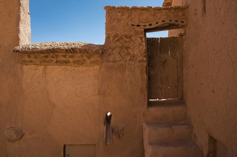Old wooden door and braun walls, detail of fortification Ajt Bin Haddu in Morocco