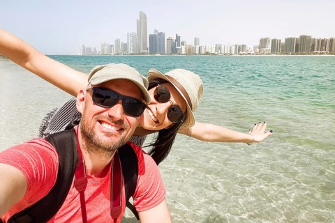 Couple of tourists having fun wave take selfie in Abu dhabi city beach on holidays in emirates -