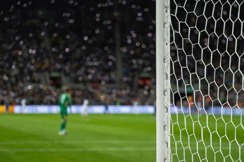 Detail of goal's post with net and football player during match in Wroclaw, Poland