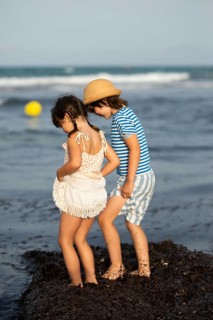 Two siblings, a girl and a boy, enjoy a playful moment by the sea during a summer beach day. The