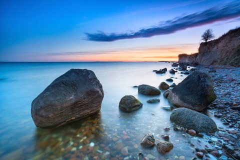 Rocky beach with large boulders on the cliffs on the Bay of Greifswald at dusk after sunset,