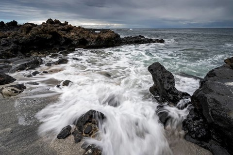 Waves blaze on the beach, rocky coast with volcanic stones, long exposure, Playa de la Pequeña,