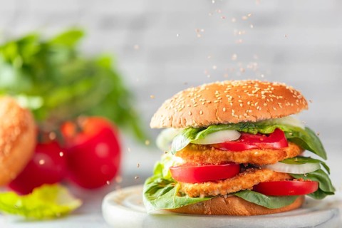 Sesame falls on burgers with vegan schnitzel, tomatoes, onions and salad with ingredients in the