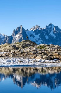 Young man in front of impressive mountain landscape in morning light, reflection in the Lac Blanc
