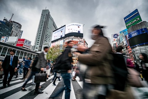 Crowd crossing zebra crossing on a large intersection, motion blur, back modern houses with