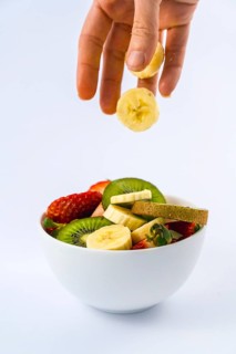 Introducing fruits with the hand of a woman, recipe of a fruit salad with kiwis, strawberries,