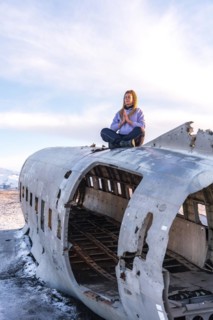 Woman sitting on the plane of Solheimasandur concentrated in meditation in Iceland