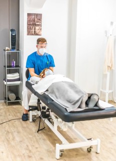 Physiotherapist with protective measures working with a patient on the stretcher, cranial