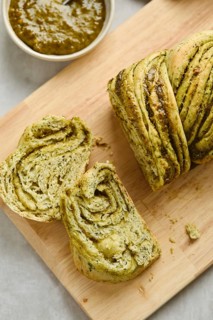 Baked homemade savoury babka plaited bread loaf flavoured with pesto on wooden bread board