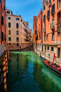 Narrow canal between colorful old houses with gondola boat in Venice, Italy