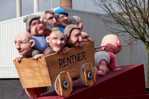 Crawling baby pulls carts full of pensioners, pension discussion, theme car by Jacques Tilly,