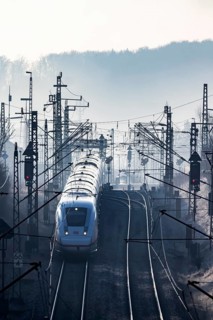 Deutsche Bahn AG tracks with ICE train against the light. Overhead line, signals and infrastructure