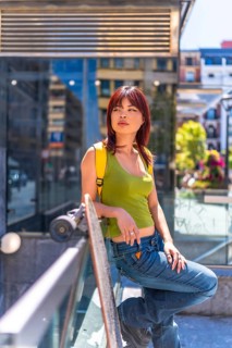 Vertical portrait of a cool asian woman standing relaxed in the city with skateboard