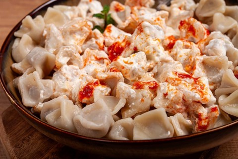 The dish features a generous serving of Turkish dumplings topped with velvety yogurt and a drizzle