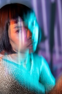A futuristic Latin woman emerges with vibrant neon lights, blurring the lines of digital and