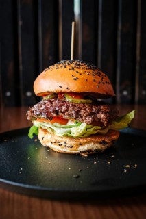 Mouthwatering hamburger served in a cozy restaurant setting. The juicy beef patty topped with fresh